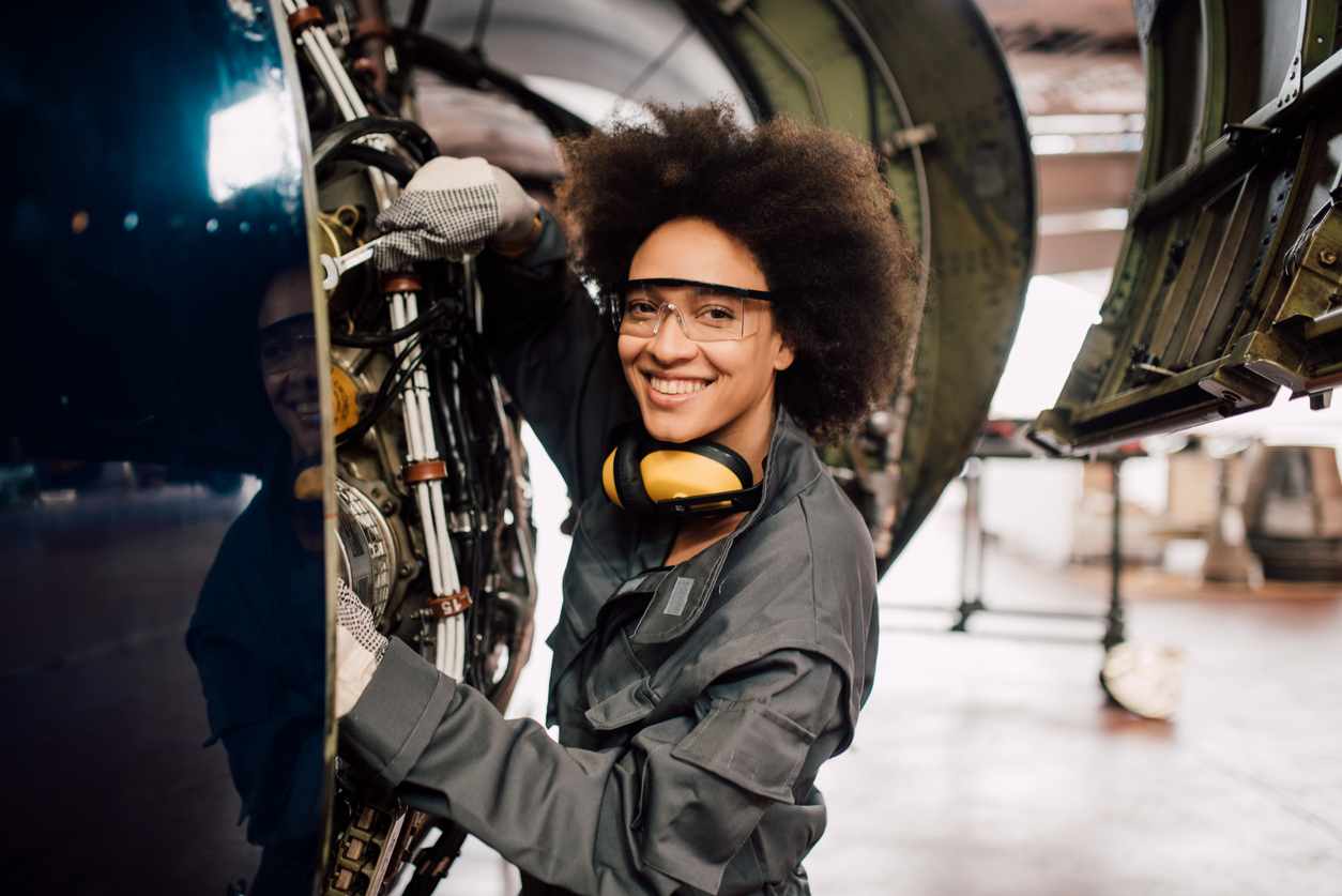 Happy young mechanic repairing airplane